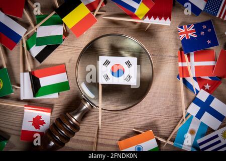 Südkoreanische Flagge und Lupe. Geschäftsmöglichkeiten, Reisen, Politik und Forschungskonzept. Flaggen verschiedener Länder auf einem hölzernen Hintergrund. Stockfoto