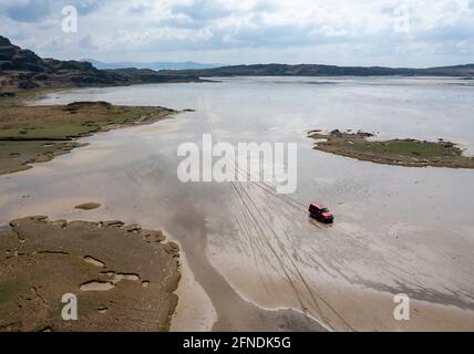 Ein Fahrzeug, das bei Ebbe über den Strand von Oransay nach Colonsay, Inner Hebrides, Argyll & Bute, Schottland, Großbritannien, fährt. Stockfoto