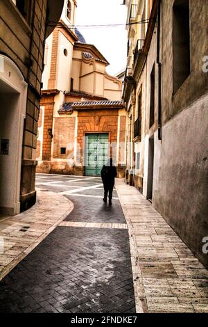 Touristischer Spaziergang durch die San Juan de Dios Straße in Murcia. Fassade aus geschnitztem Stein und alte Holztür an der Kirche San Juan de Dios. Stockfoto