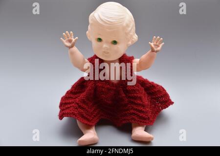 Eine Nahaufnahme von gruseliger alter Puppe in rotem Kleid isoliert Auf grauem Hintergrund Stockfoto