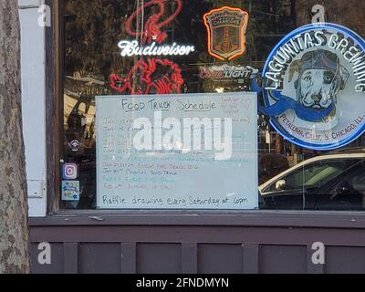 Nahaufnahme eines Schildes im Fenster des Round Up Saloon, auf dem der Fahrplan des Food-Trucks zu sehen ist, in Lafayette, Kalifornien, 20. Januar 2021. () Stockfoto