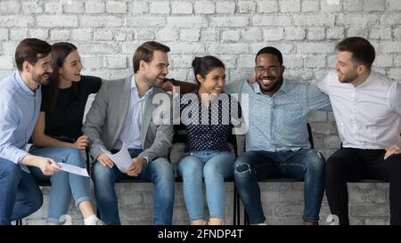 Glücklich aufgeregt vielfältige Gruppe von professionellen Freunden sitzen auf Stühlen Stockfoto