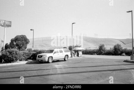 Schwarz-Weiß-Foto eines Kleinwagens mit einem Schild, auf dem das Holiday Inn Express und einige Berge im Hintergrund abgebildet sind, 15. August 2020. () Stockfoto