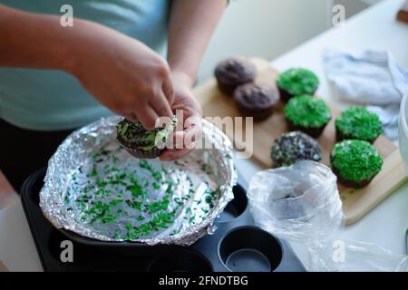 Asiatische philippinische Frau, die zu Hause in Ottawa, Ontario, Kanada, mit Prise auf Cupcakes bestreut Stockfoto