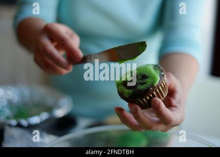 Asiatische Filipinerin, die zuhause in Ottawa, Ontario, Kanada, Puderzucker auf Cupcakes streut Stockfoto