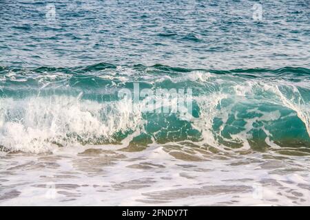 Tidalbohrung. Blaue Wellen mit Fledermäusen, die an einen Sandstrand Rollen. Stockfoto