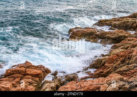 Tidalbohrung. Schaumig blaue Wellen krachen auf Küstenklippen. Stockfoto