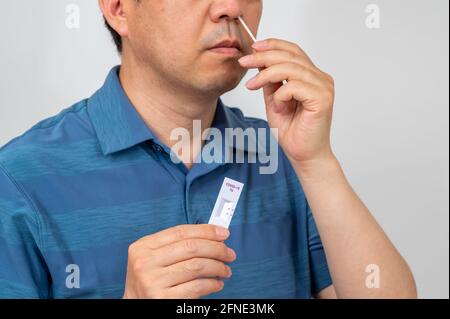 Asiatischer Mann mittleren Alters wurde mit COVID-19 Home-Antigen-Kits auf Coronavirus getestet. Stockfoto