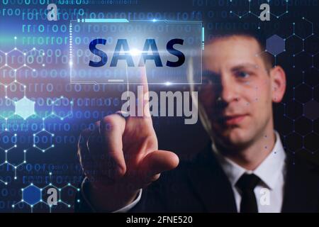 Business, Technologie, Internet und Netzwerkkonzept. Junger Geschäftsmann arbeitet auf einem virtuellen Bildschirm der Zukunft und sieht die Inschrift: SAAS Stockfoto