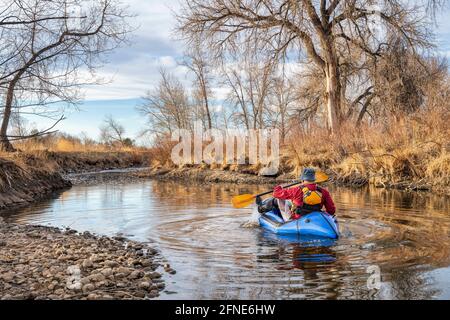 Älterer Rüde paddelt ein aufblasbares Packfloß auf einem Fluss Im Frühjahr - Poudre River im Norden von Colorado Stockfoto