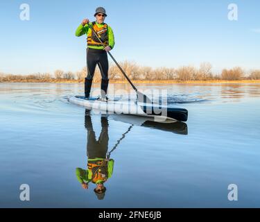 Der ältere Stand Up Paddler beginnt seine Paddelsaison Auf einem See in Colorado Stockfoto