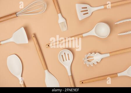 Muster aus Kochgeschirr-Set. Küchengeräte aus Silikon mit Holzgriff auf beigem Hintergrund. Draufsicht Flat Lay. Stockfoto