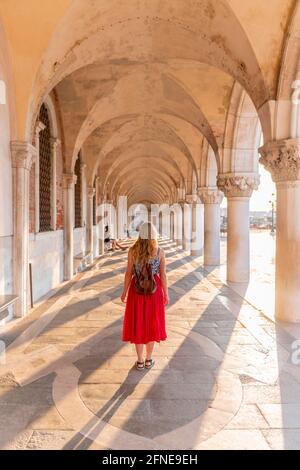 Junge Frau im Portikus am Dogenpalast, Markusplatz, Venedig, Venetien, Italien Stockfoto