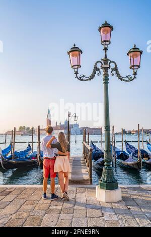 Junges Paar vor einem Steg, venezianische Gondeln, Blick auf die Kirche San Giorgio Maggiore, Venedig, Venetien, Italien Stockfoto