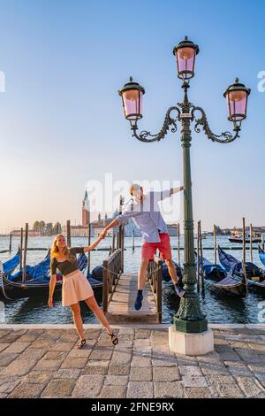 Junges glückliches Paar vor einem Steg, venezianische Gondeln, in der hinteren Kirche San Giorgio Maggiore, Venedig, Venetien, Italien Stockfoto
