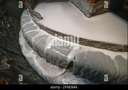 Flotationsmaschine. Von der Trennkante des Bades fließt ein Strahl grauer, schmutziger Flüssigkeit herunter Stockfoto