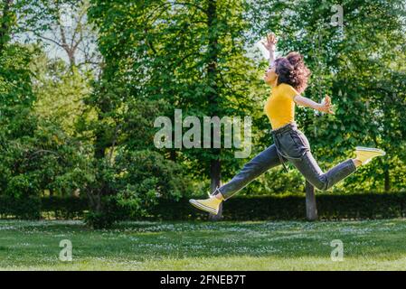 Hübsche Frau, die glücklich in einem Garten springt. Stockfoto