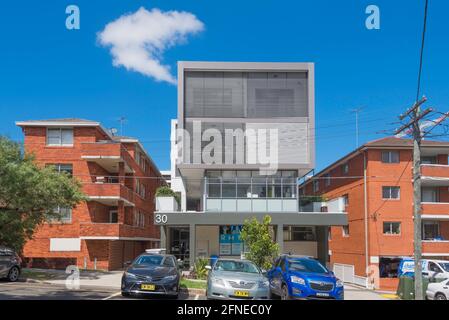 Ein großer neuer Apartmentblock mit Balkonen, die von louvre-Bildschirmen bedeckt sind, zwischen zwei gemauerten und gefliesten Apartmentblöcken aus den 1970er Jahren mit großen offenen Balkonen. Stockfoto