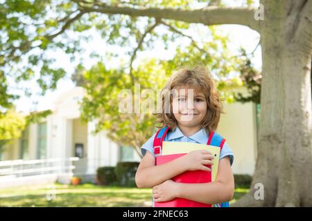 Wissenstag. Kind geht zum Studium. Schuljunge mit Rucksack geht auf grünem Rasen. Frohe Kindheit. Grundschulbildung. Stockfoto