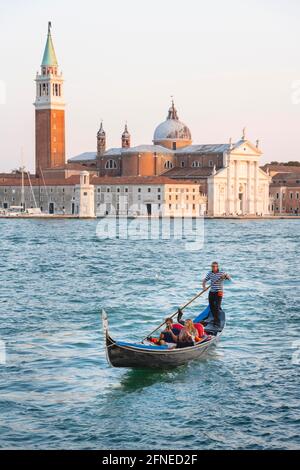 Gondoliere rudert in venezianischer Gondel am Meer, Blick auf die Kirche San Giorgio Maggiore, Venedig, Venetien, Italien Stockfoto