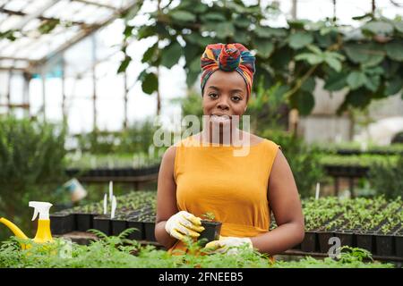 Porträt einer jungen afrikanischen Frau, die während der Arbeit die Kamera anlächelt Im Garten Stockfoto