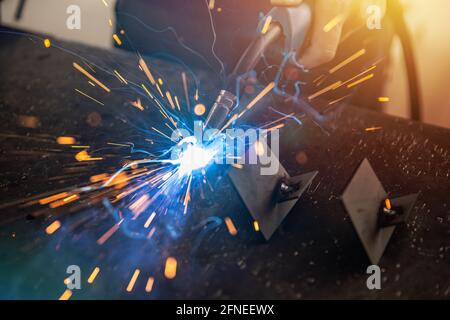Industriearbeiter beim Schweißen von Eisenstücken bei der Arbeit. Metallverarbeitung Herstellung und Bau Wartung Service Stockfoto