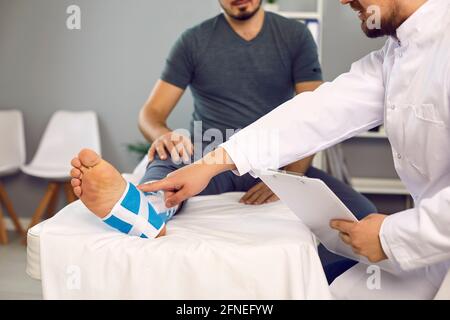 Arzt und Patient mit gebrochenem Bein Fuß Knöchel in orthopädischen Pflegeverband Stockfoto