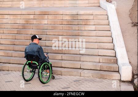 Eine junge behinderte Person im Rollstuhl kann die Treppe nicht betreten. Zugängliche Umgebung für Behinderte Stockfoto