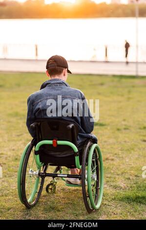Nahaufnahme. Behinderter Mann auf Rollstuhl im Freien. Behinderter Junger Mann. Mann auf dem Rollstuhl. Konzepte für die Wiederherstellung und das Gesundheitswesen Stockfoto