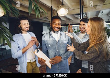 Das Büroteam begrüßt den neuen afroamerikanischen männlichen Mitarbeiter Stockfoto