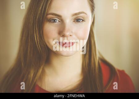 Kopfaufnahme einer intelligenten selbstbewussten lächelnden tausendjährigen europäischen Frau Stehen mit gefalteten Armen zu Hause Stockfoto