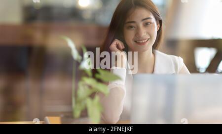Ausgeschnittene Aufnahme einer Geschäftsfrau, die in der zur Kamera lächelt Während der Arbeit an ihrem Projekt Stockfoto