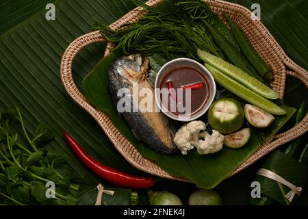 Draufsicht auf gebratene Makrele mit Shrimp Paste Sauce und Gemüseset auf Weidenschale serviert Stockfoto