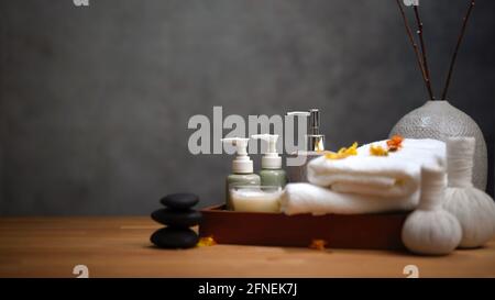 Spa-Tisch mit Massagestein und Handtüchern auf Holztisch, Spa-Therapie-Konzept Stockfoto