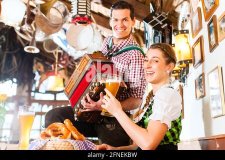 Bayerischen Mann spielt Volksmusik für Frau trägt dirndl Stockfoto