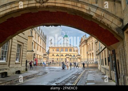 Touristen in der Bodleian-Bibliothek, mit dem Sheldonian-Theater im Hintergrund, von der Seufzerbrücke, dem Hertford College und der Universität Oxford aus gesehen. Stockfoto