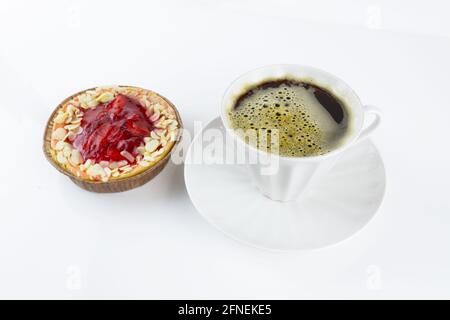 Erdbeertarte mit Mandelblüten und weißer Porzellanbecher mit Kaffee und Untertasse auf weißem Hintergrund Stockfoto