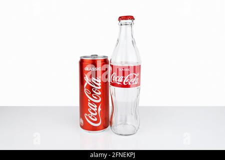 Leere Glasflasche und Blechdose von Coca Cola in rotem Design auf weißem Hintergrund. - Russland, St. Petersburg, Februar 2021 Stockfoto