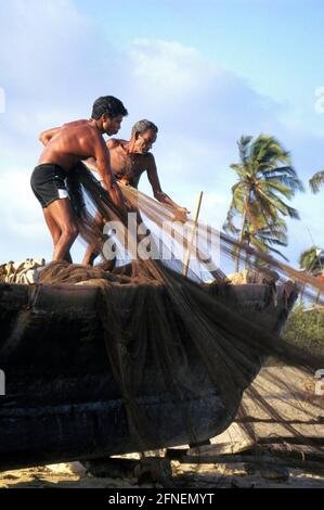 Vater und Sohn sortieren die Netze für den nächsten Fang. Neben dem Tourismus sind Fischerei, Landwirtschaft und Viehzucht die wichtigsten Einkommensquellen für die Menschen im indischen Bundesstaat Goa.n [automatisierte Übersetzung] Stockfoto