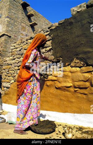 Frauen in Indien sind in allen Berufen zu finden. Ob im Straßenbau oder in der Politik, Frauen in Indien scheinen oberflächlich gleich zu sein. Diese Rajasthani verputzt die Außenwände ihres Hauses, Fassadendekoration ist ein Frauengeschäft in Indien. [Automatisierte Übersetzung] Stockfoto