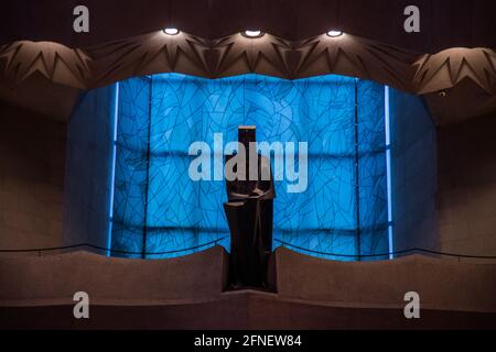 Ein winkliger, batman-ähnlicher Jesus, der vom Ende des Kirchenschiffs aus das Innere der Basilika de la Sagrada Familia überblickt und von einem noch unfinishen Fleck hinterleuchtet ist Stockfoto