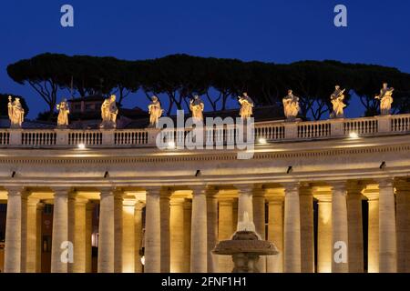 Vatikan, monumentale Kolonnade von Bernini, die nachts auf dem Petersplatz beleuchtet wird, Säulen im dorischen Stil und Heiligenstatuen auf der Spitze. Stockfoto