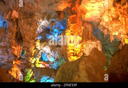 Stalaktitenhöhle, die von farbigen Scheinwerfern auf Hang Dau Go (Insel der Holzpfosten), einer der vielen Inseln in der Halong Bay im Nordosten Vietnams, beleuchtet wird. [Automatisierte Übersetzung] Stockfoto