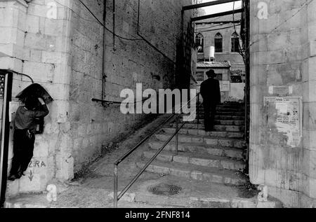 Treppe im Jerusalemer Stadtteil Mea Sharim, bewohnt von überwiegend orthodoxen Juden. Ein kleiner Junge stiehlt Geld von einem öffentlichen Telefon. [Automatisierte Übersetzung] Stockfoto