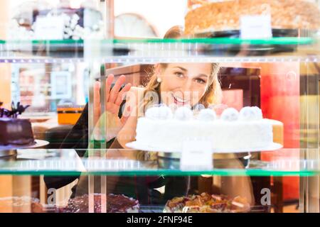 Frau Auswahl einen Kuchen aus der Konditorei Glas Anzeige Stockfoto