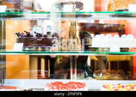 Frau Auswahl einen Kuchen aus der Konditorei Glas Anzeige Stockfoto