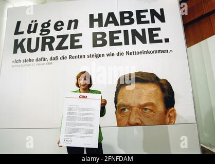 'CDU-Generalsekretärin Angela Merkel präsentiert ein Plakat der CDU zur ''Pensionslüge''. Das Plakat zeigt Gerhard Schröders Porträt und die Inschrift "Lügen haben kurze Beine. „Ich stehe für steigende Renten wie die Nettoeinkommen. ''Gerhard Schröder, 17. Februar 1999.'' [Automatisierte Übersetzung]' Stockfoto