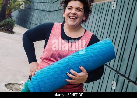 Übergewichtige Frau, die beim Sport lacht. Adiposity Training in Positivität. Körperakzeptanz Stockfoto
