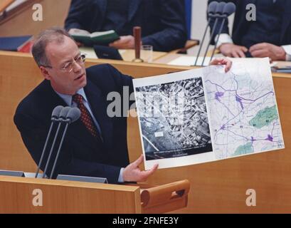 Das Foto zeigt Bundesverteidigungsminister Rudolf Scharping bei einer Sondersitzung im Bundestag zum Thema Kosovo. Er zeigt auch Fotos von den Verwüstungen im Kosovo. Der Grund für diese Rede war der Kosovo-Konflikt, der vom 28.2.1998. Bis 10.6. 1999 andauerte. In diesem bewaffneten Konflikt ging es um die Kontrolle des Kosovo, unter den verschiedenen Parteien waren die Befreiungsarmee des Kosovo, die jugoslawische Armee, serbische Ordnungskräfte sowie NATO-Truppen unter der Führung der USA. Kosovo war früher eine Provinz Serbiens mit einer Mehrheit der albanischen Bevölkerung innerhalb Jugoslawiens. [Automatisiert Stockfoto