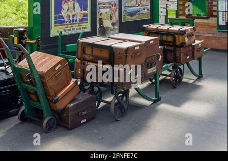 Trolleys, die mit alten Koffern auf dem Bahnsteig des Bahnhofs Loughborough beladen sind, der Teil der Great Central Railway, Großbritannien, ist Stockfoto